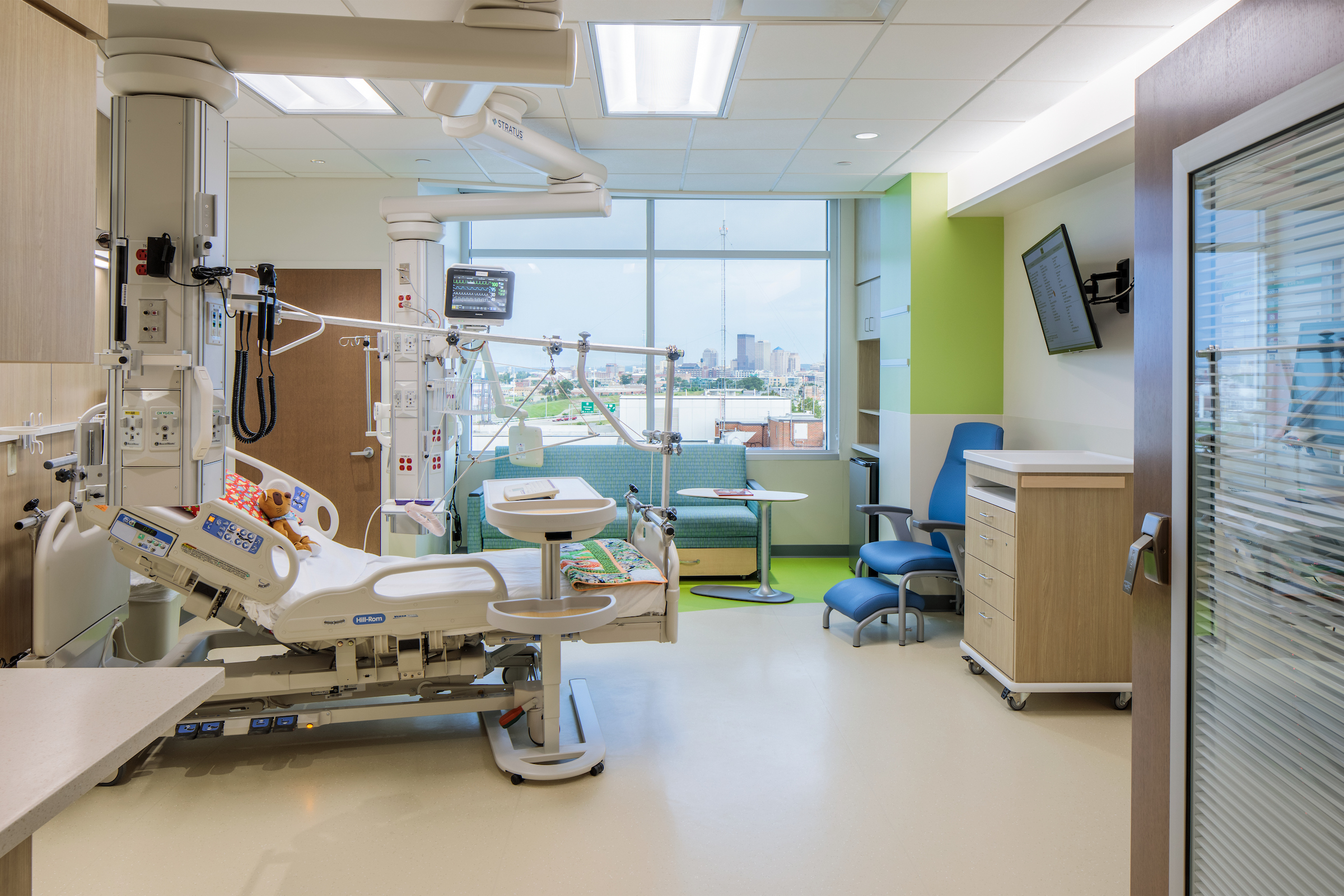 Bright, private inpatient room with medical equipment and hospital bed with a view of the city.