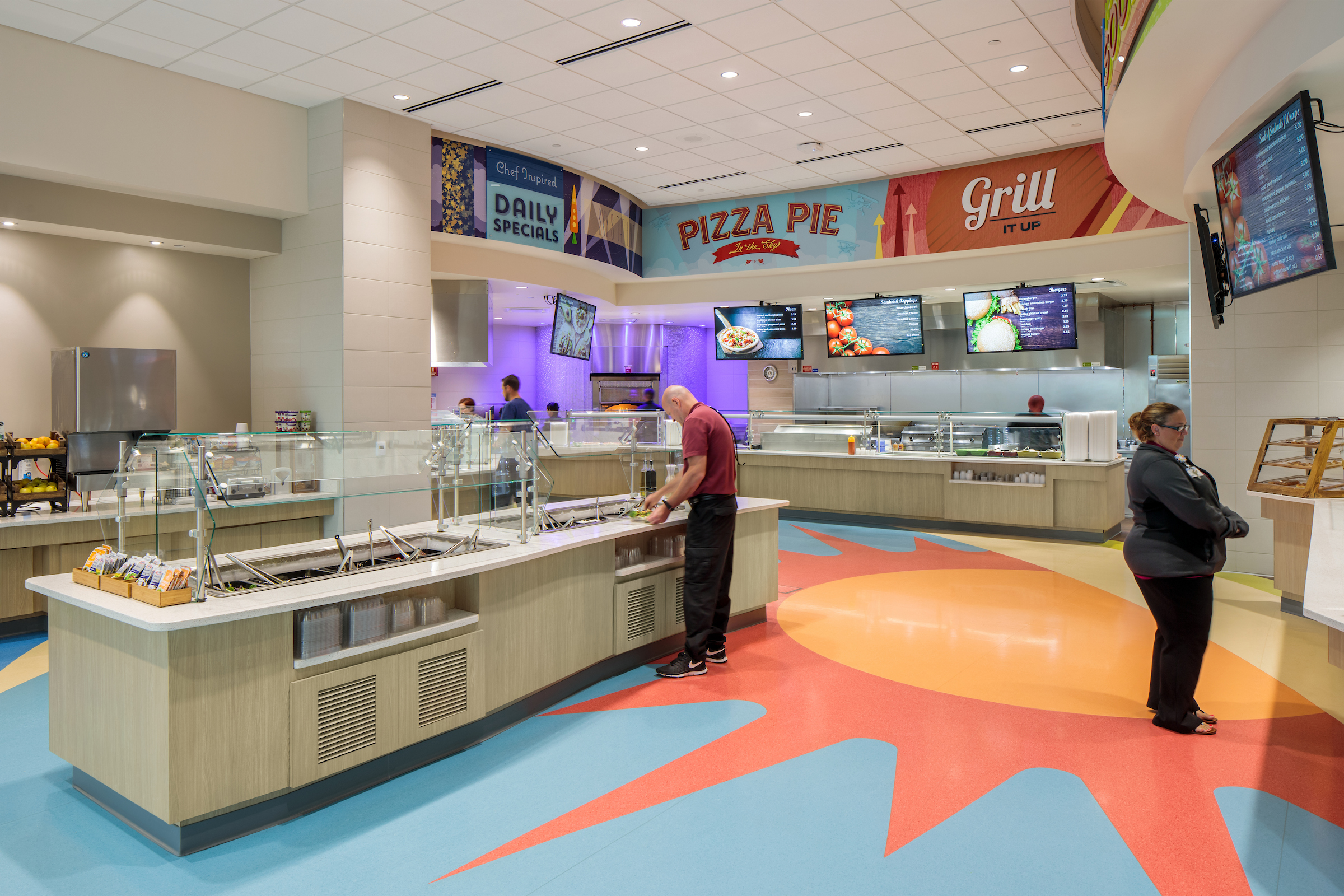 Bright, colorful cafeteria at main campus with multiple stations for food.