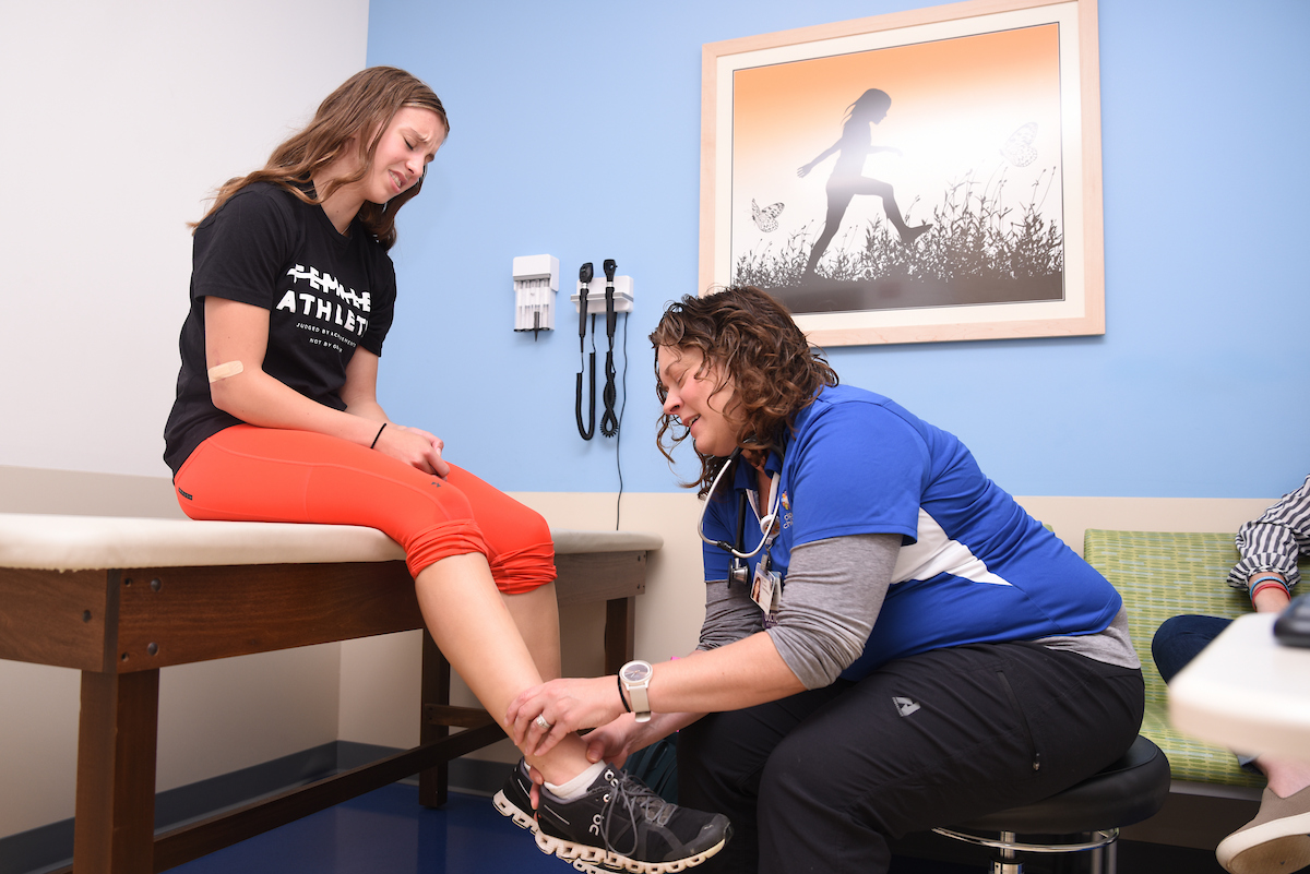 teen female athlete being seen by doctor in after-hours ortho clinic after a sports injury