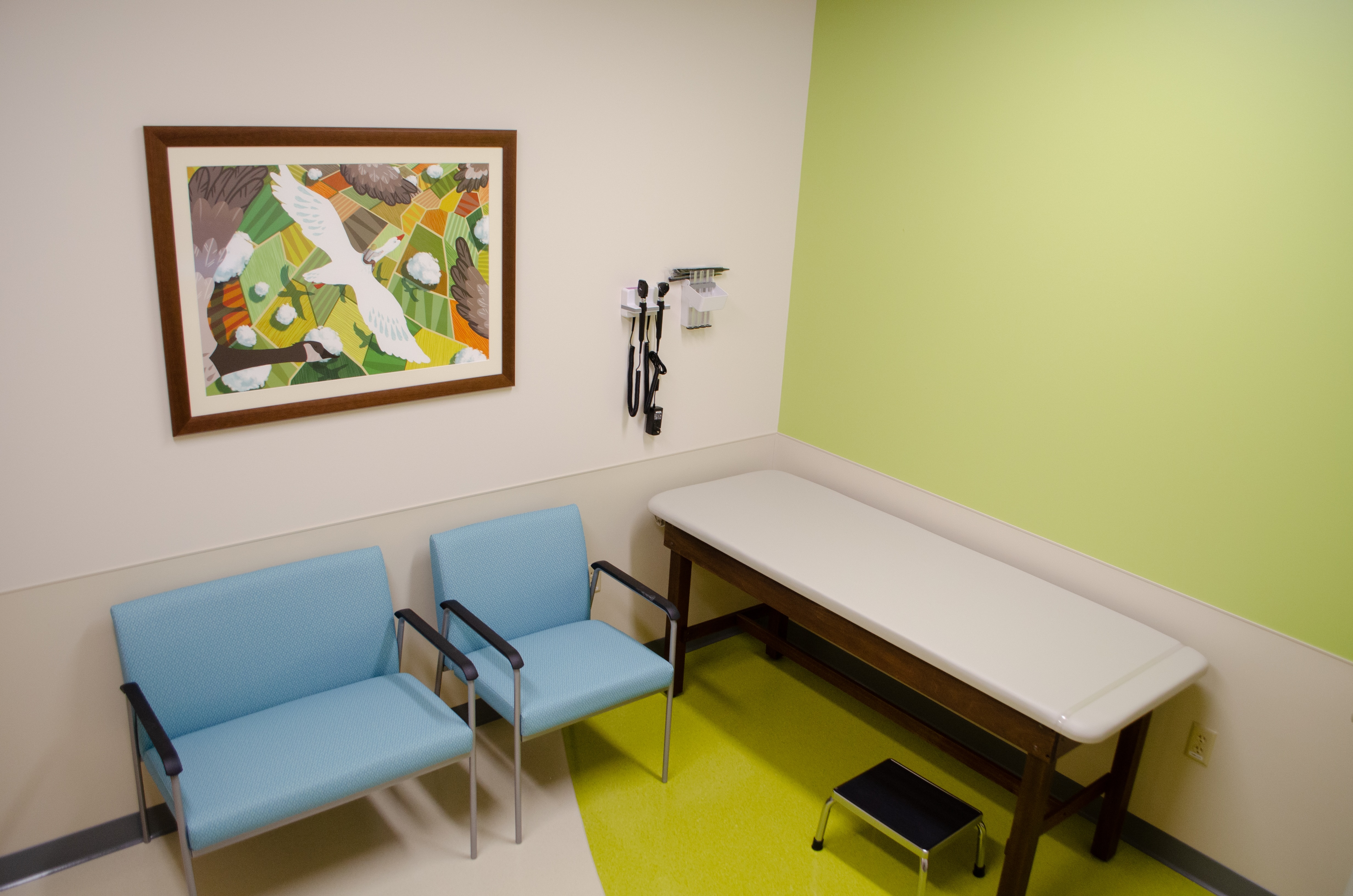 Dayton Children's exam room with a green wall and two chairs with kid-friendly art.